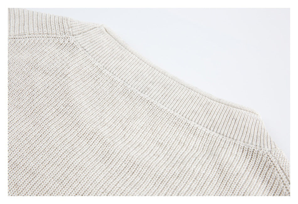 Close-up of an ivory sweater neckline with a ribbed collar and shoulder seam.