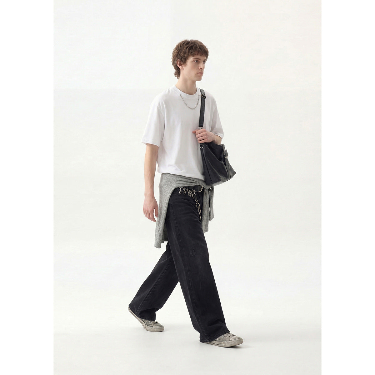 Model wearing a plain white crew-neck T-shirt with loose black trousers, shown from the front.