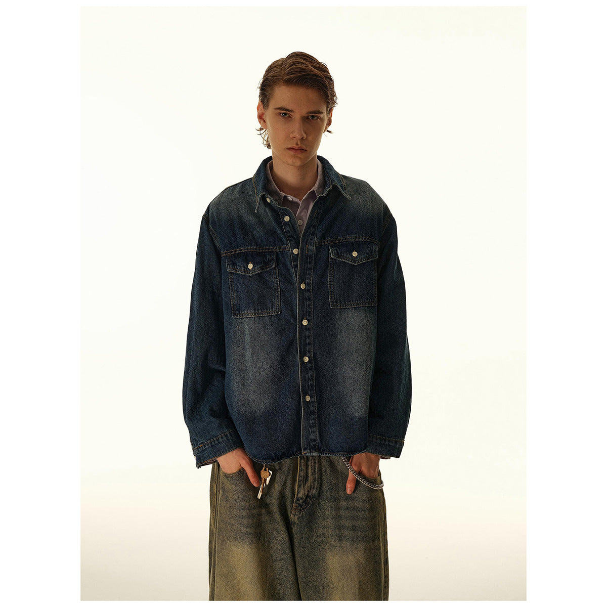 Closer front view of a man in a dark blue denim overshirt with two button-flap chest pockets.