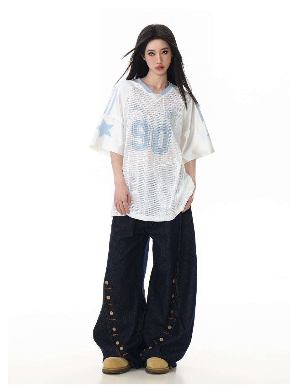 Model wearing the white mesh V-neck jersey tee with light blue '90' print, star sleeve and wide-leg dark jeans, full-length