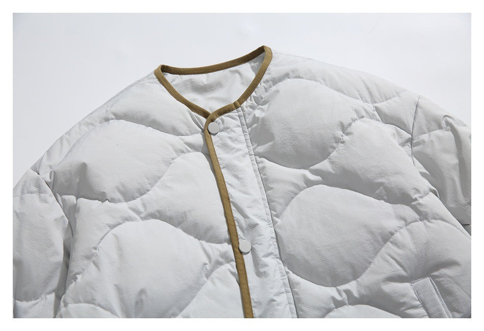 Close-up of the light gray jacket's quilted front, round neckline, olive-brown edging, and snap closure.