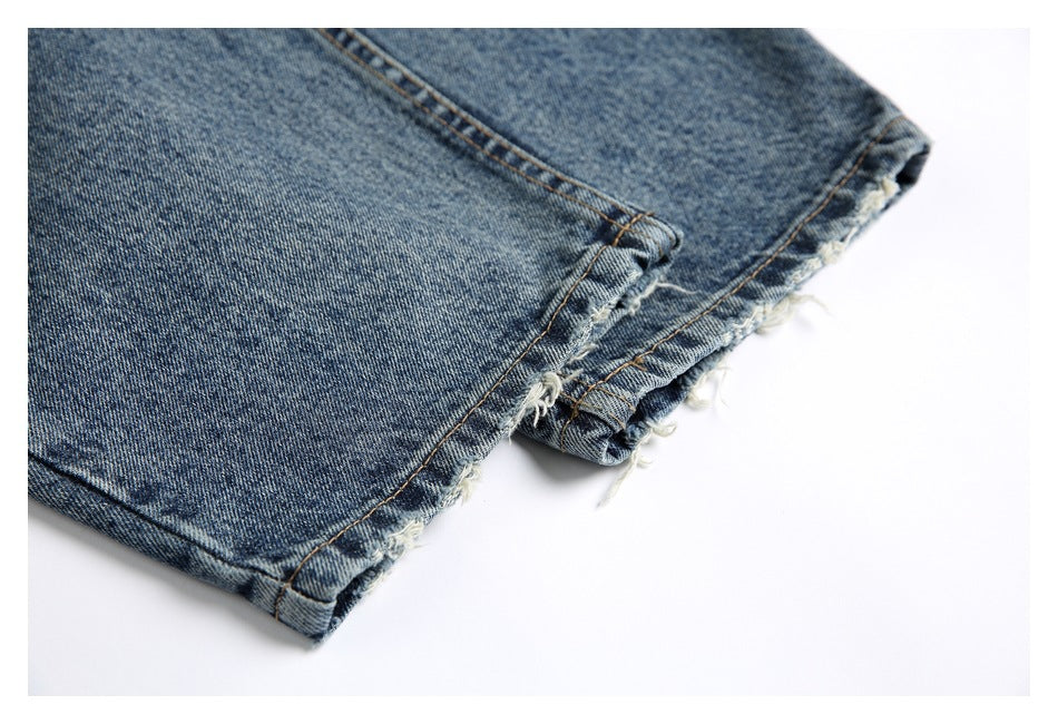 Close-up of the frayed, unfinished hem on blue denim jeans.