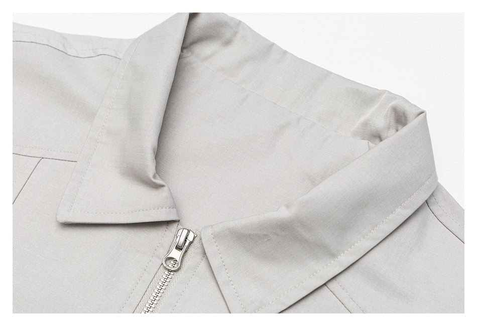 Close-up of the light gray jacket's pointed collar and front zipper.