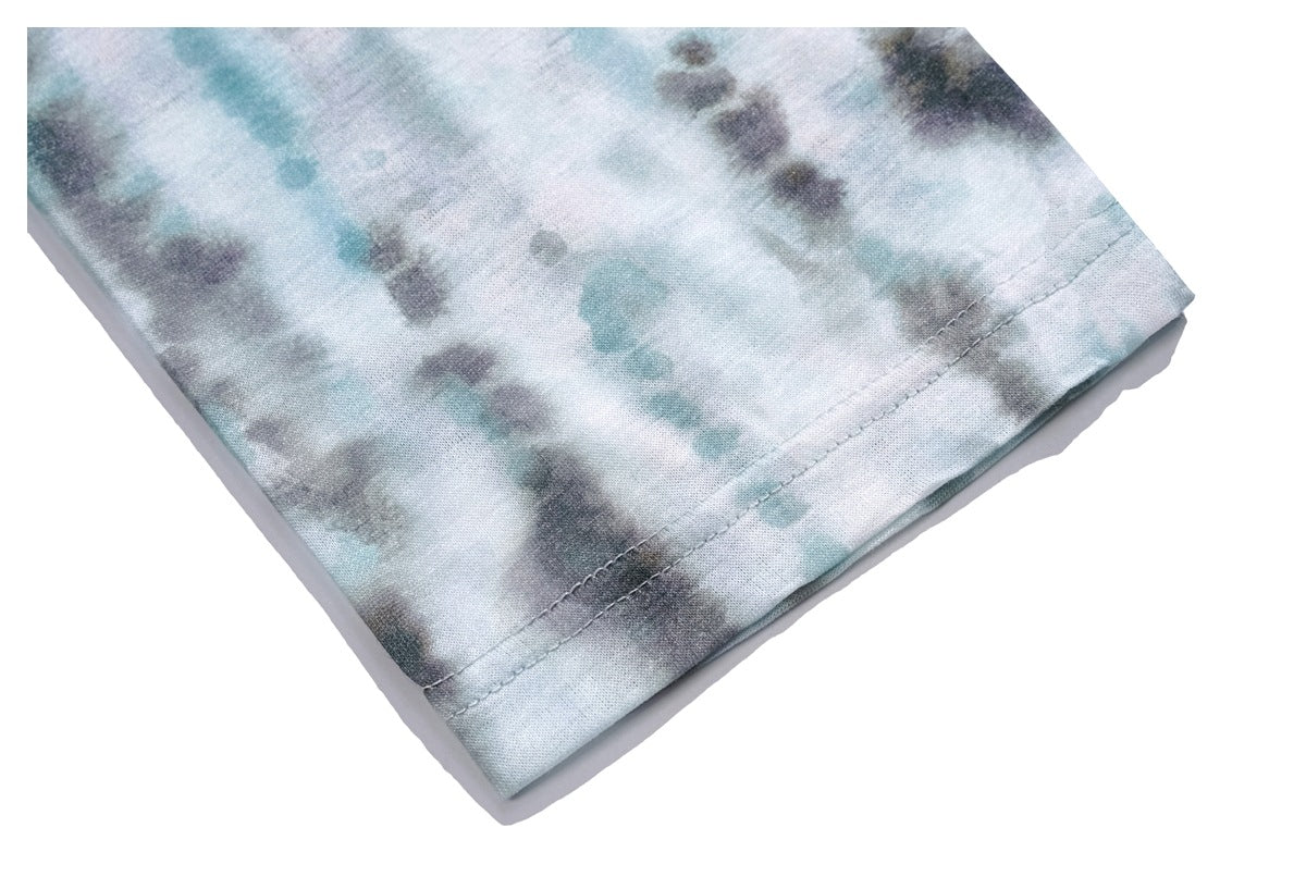 Close-up of a stitched hem on pale aqua and gray tie-dye fabric.