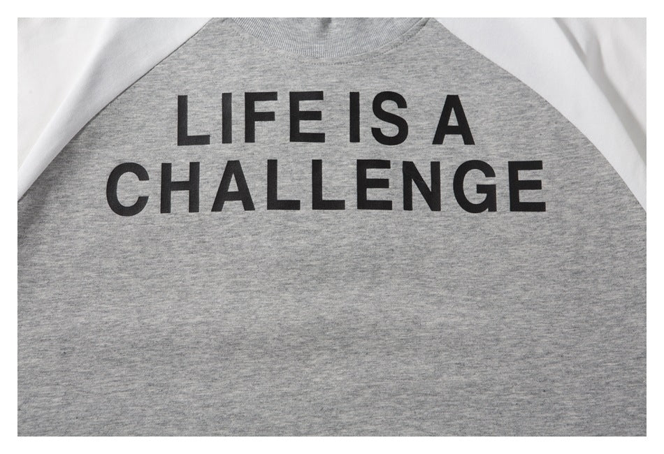 Close-up of the black “LIFE IS A CHALLENGE” print on the gray sweatshirt front.