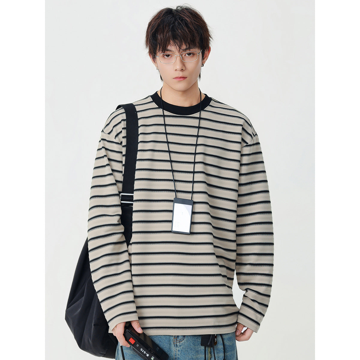 Model wearing an oversized beige long-sleeve shirt with thin black horizontal stripes and a black crew neck.