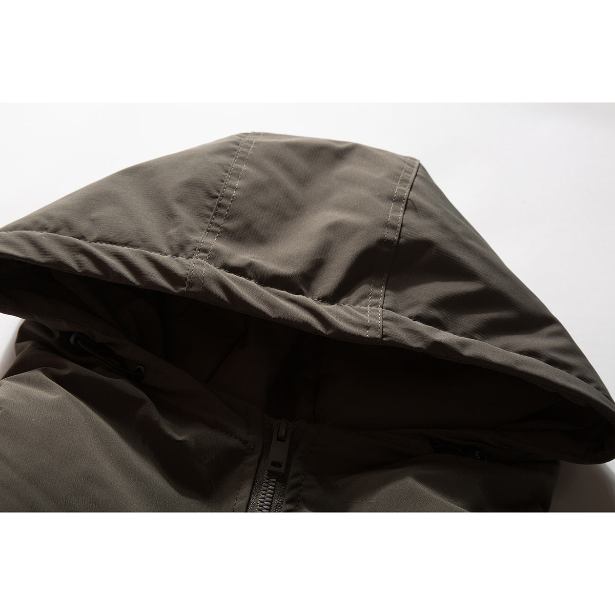 Close-up of a charcoal-brown jacket hood, stitching, drawcord, and front zipper.