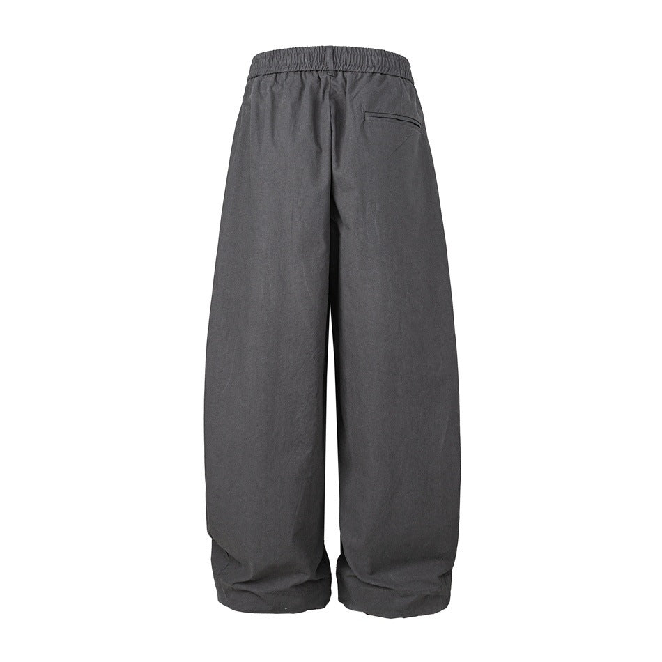 Back view of charcoal wide-leg trousers with an elastic waistband and a small welt pocket.