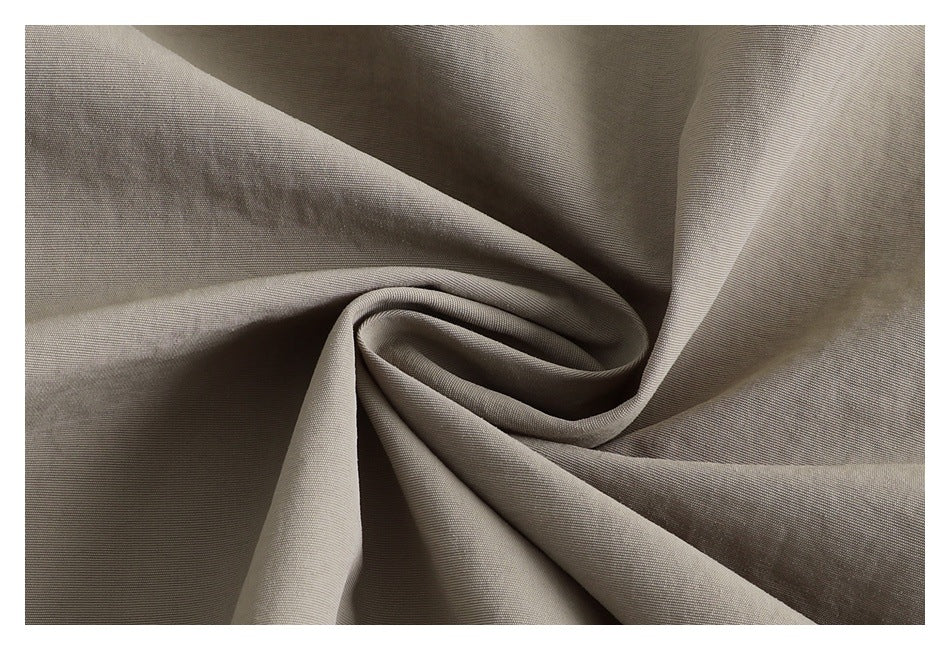 Close-up of taupe fabric gathered into soft folds, showing its surface texture.