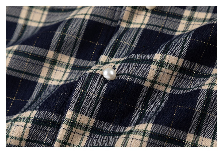 Close-up of navy, cream, and muted green plaid fabric with a pearl-like button.