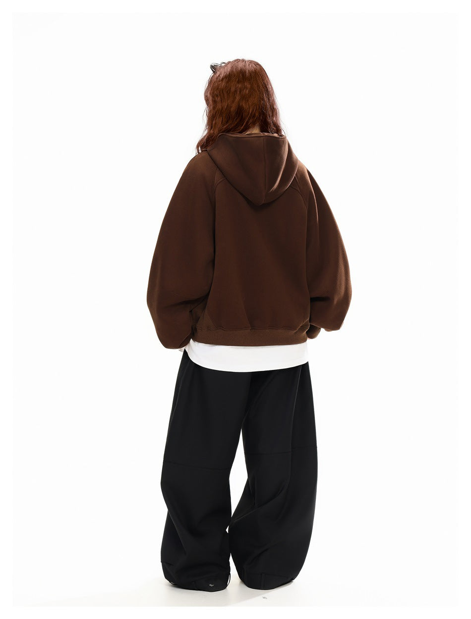 Rear view of a model wearing a dark brown hooded jacket with oversized sleeves.