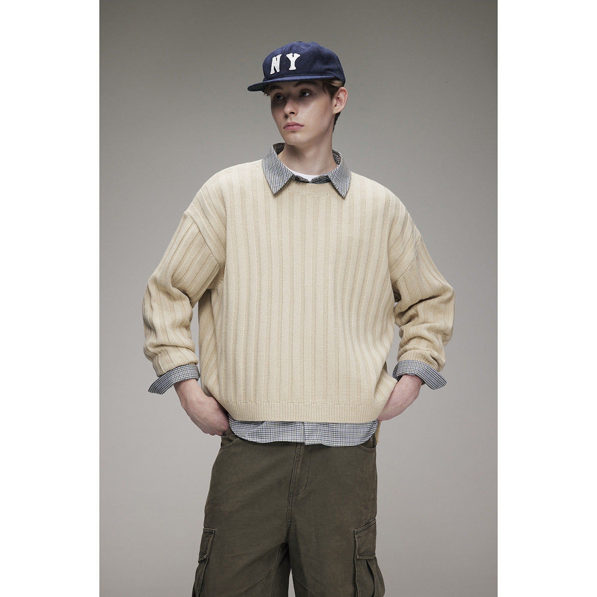 Front view of a model wearing a cream ribbed sweater over a checked shirt.