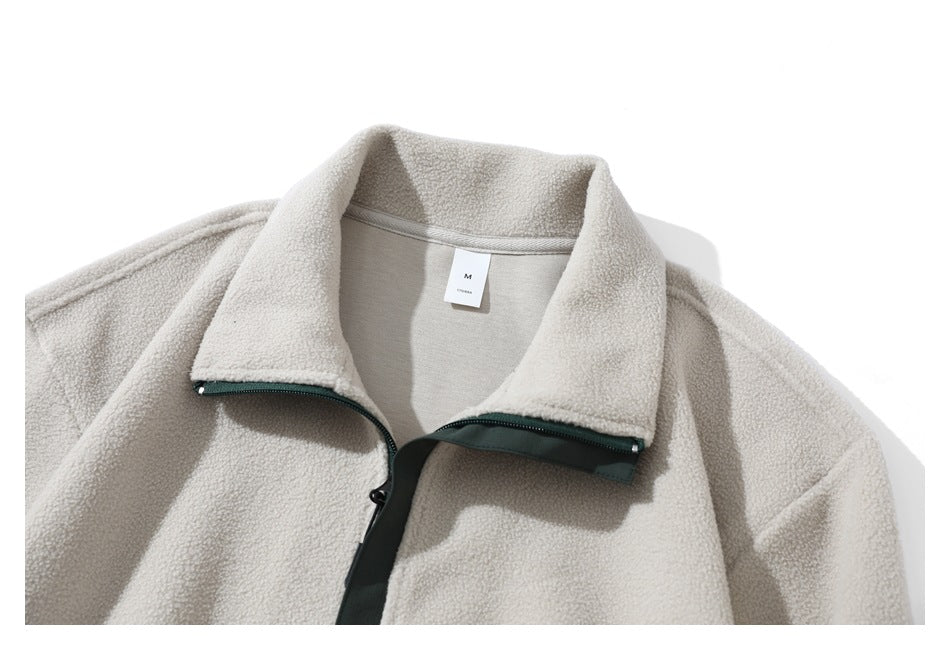 Close view of a cream sherpa jacket front with a wide collar and dark green zipper trim.