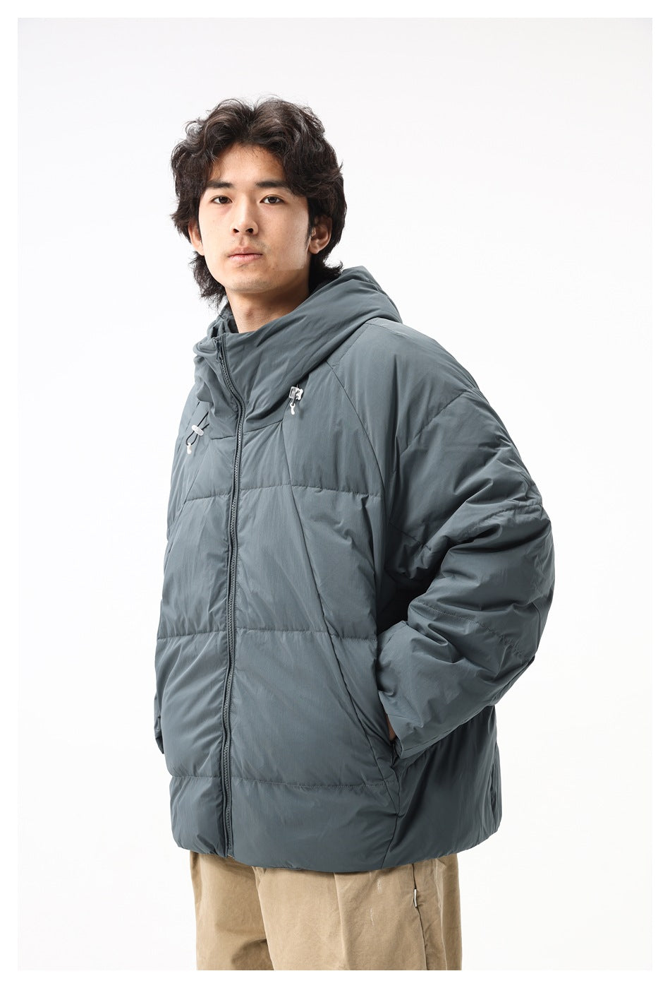 Model wearing a slate gray hooded puffer jacket with a front zipper and drawcords, shown at a three-quarter angle.