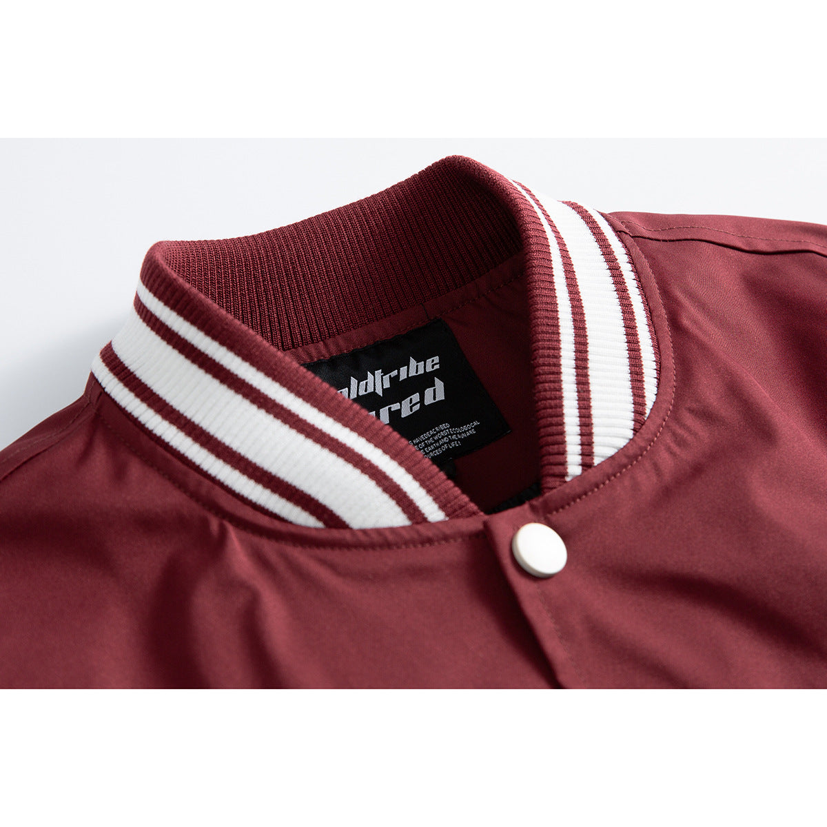 Close-up of a burgundy jacket’s striped rib-knit collar, snap button, and inner neck label.