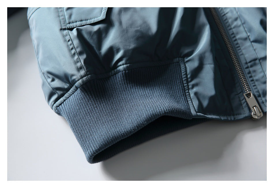 Close-up of a blue-gray jacket sleeve cuff with ribbed trim, stitching, and a metal zipper.