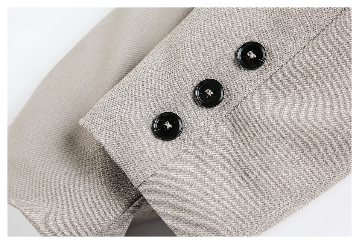 Close-up of three black buttons on a taupe jacket sleeve tab.