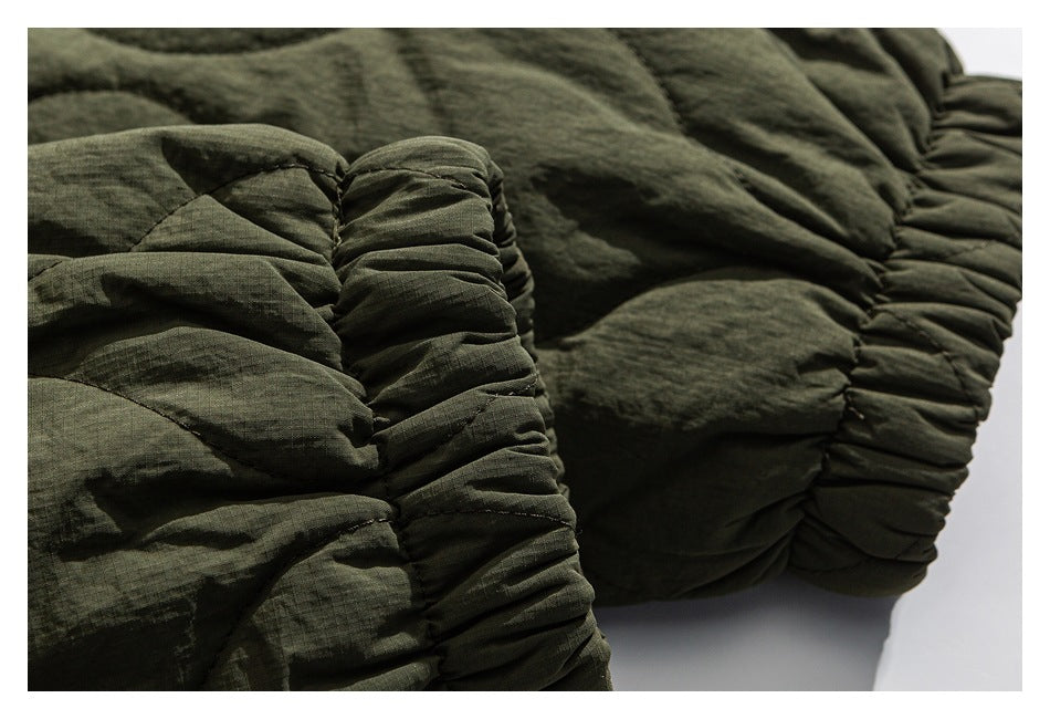 Close-up of an olive-green quilted jacket showing a gathered elastic cuff and padded stitching.