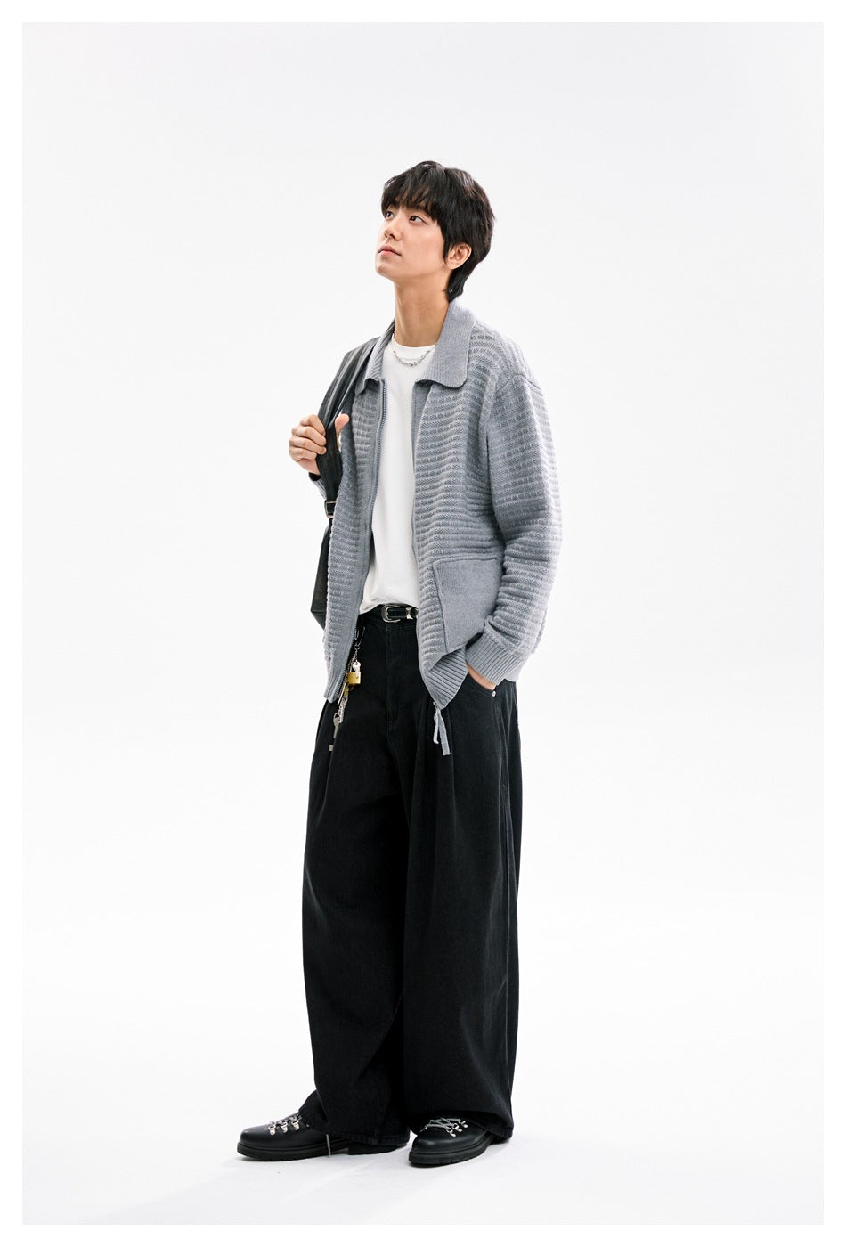 Model wearing a light gray textured collared cardigan over a white shirt and wide black trousers.