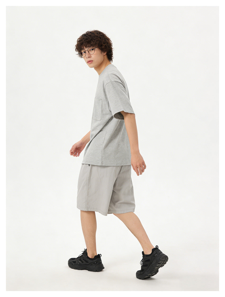 Model in a light gray pocket T-shirt and gray shorts, shown at an angled side view.