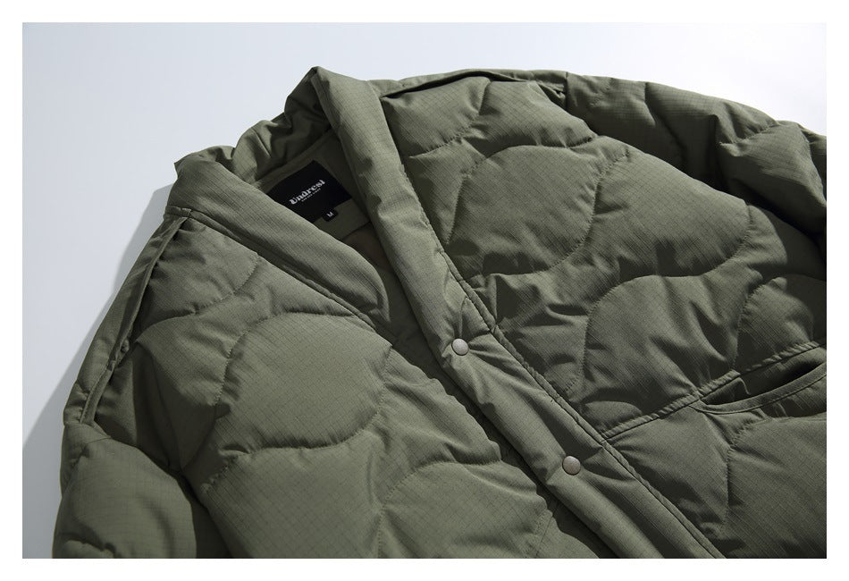 Close-up of the olive-green jacket's quilted front, snap-button placket and interior neck label.