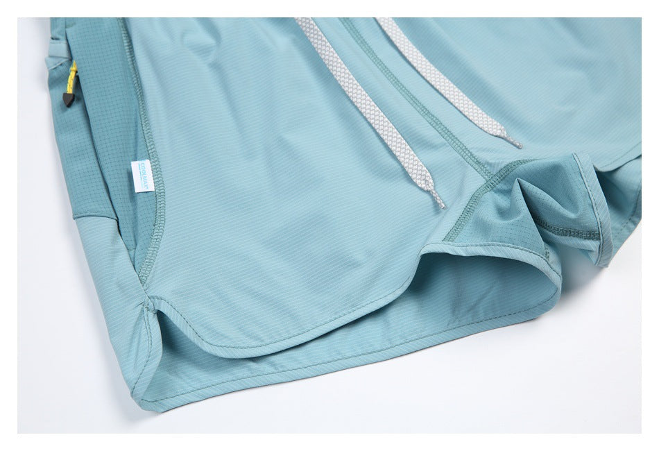 Close-up of aqua athletic shorts showing the curved hem, stitching, side pocket, and drawcords.