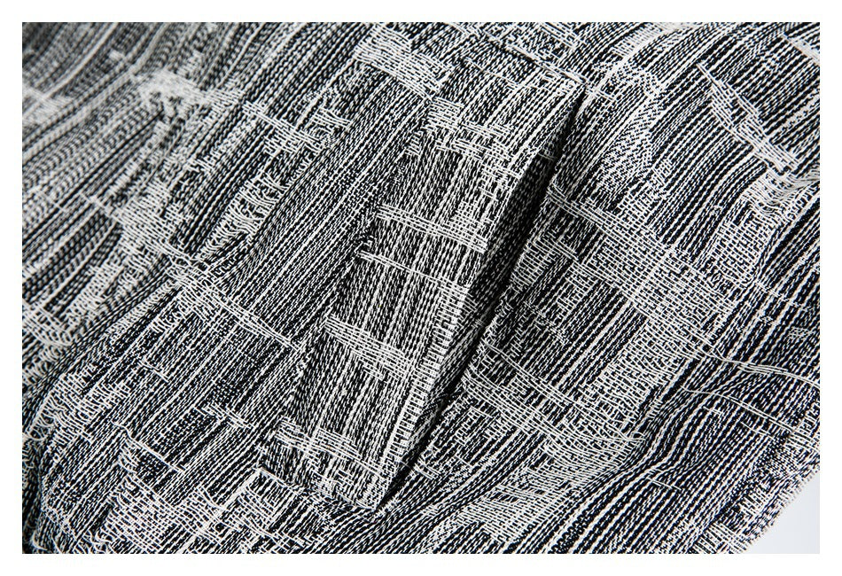 Close-up of the garment’s black-and-white textured fabric and a raised folded seam.
