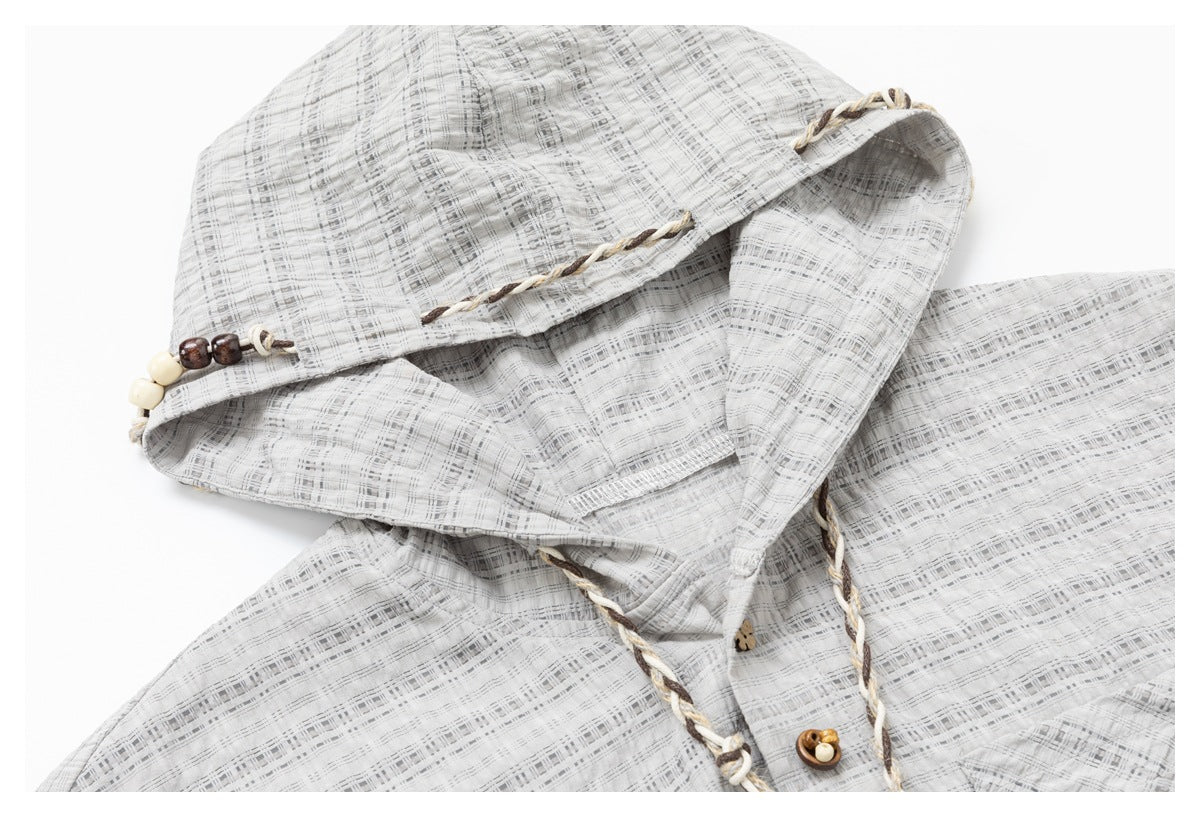 Close-up of the jacket's checked hood, braided trim, beaded accents, and upper front buttons.