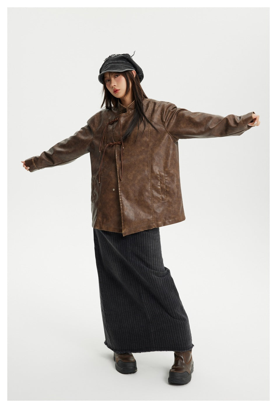 Full-length view of a model wearing a brown tie-front jacket and long black ribbed skirt.