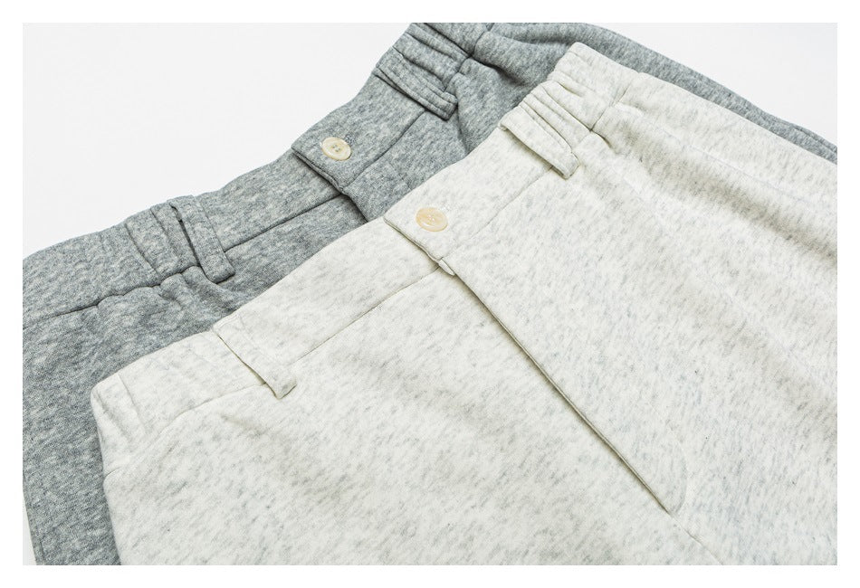 Waist details of overlapping gray and pale heathered trousers, with buttons, belt loops, and fly fronts.
