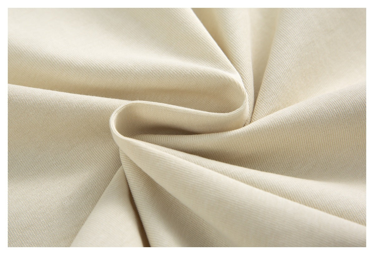 Close-up of cream-colored fabric draped into soft folds, showing a fine textured weave.