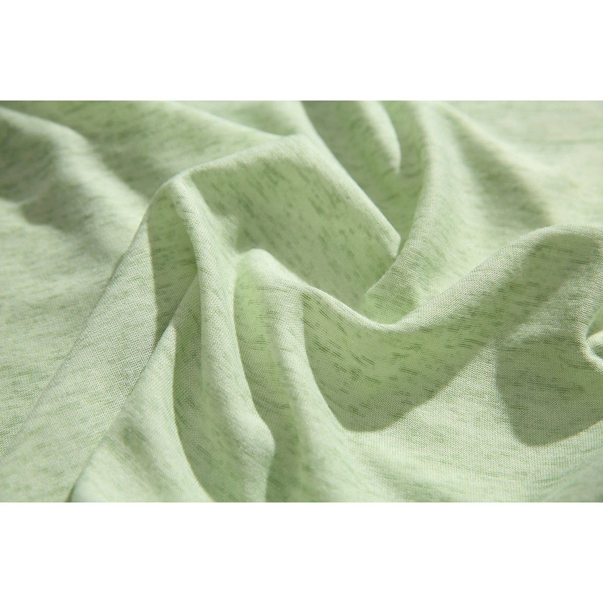 Close-up of the pale green shirt fabric, shown loosely draped to reveal its surface texture.