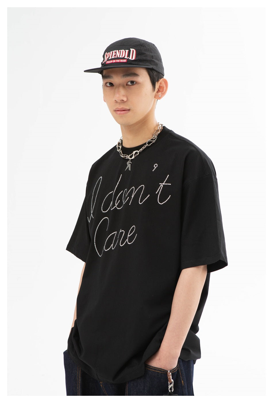 Angled view of a model wearing an oversized black T-shirt with rhinestone “I don't care” script.