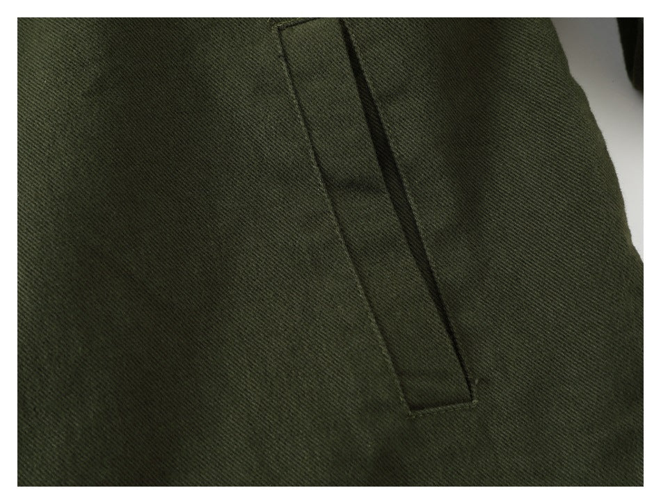 Close-up of dark olive garment fabric with a narrow vertical welt pocket.