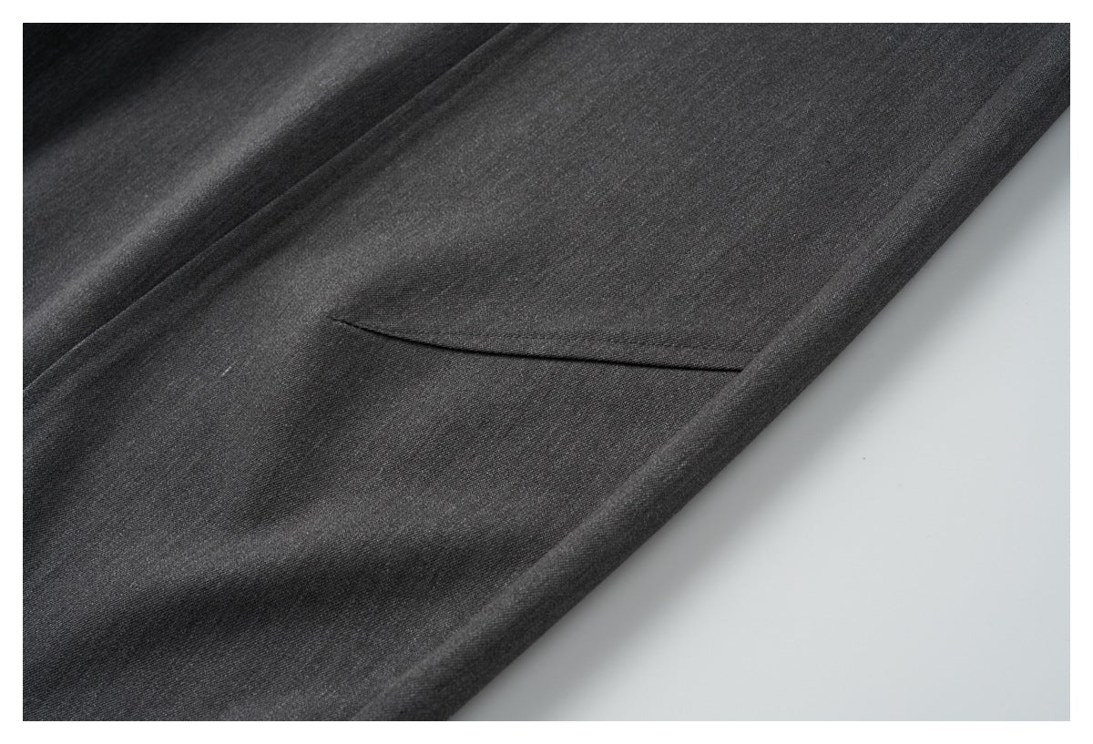 Close-up of charcoal trousers showing a slanted side pocket and smooth fabric.