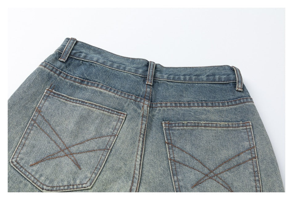 Partial back view of faded blue jeans with belt loops and two rear pockets with angular stitching.