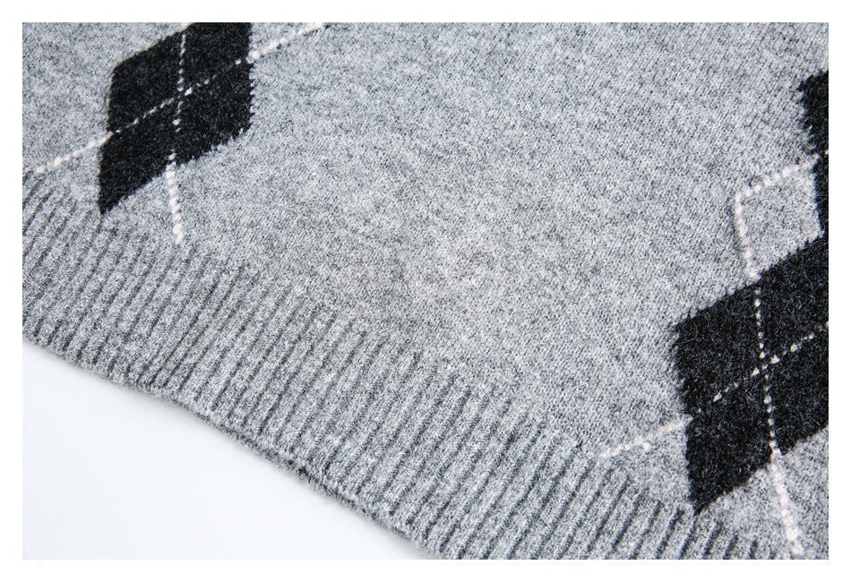Close-up of a gray marled sweater's ribbed hem with black argyle diamonds at the sides.