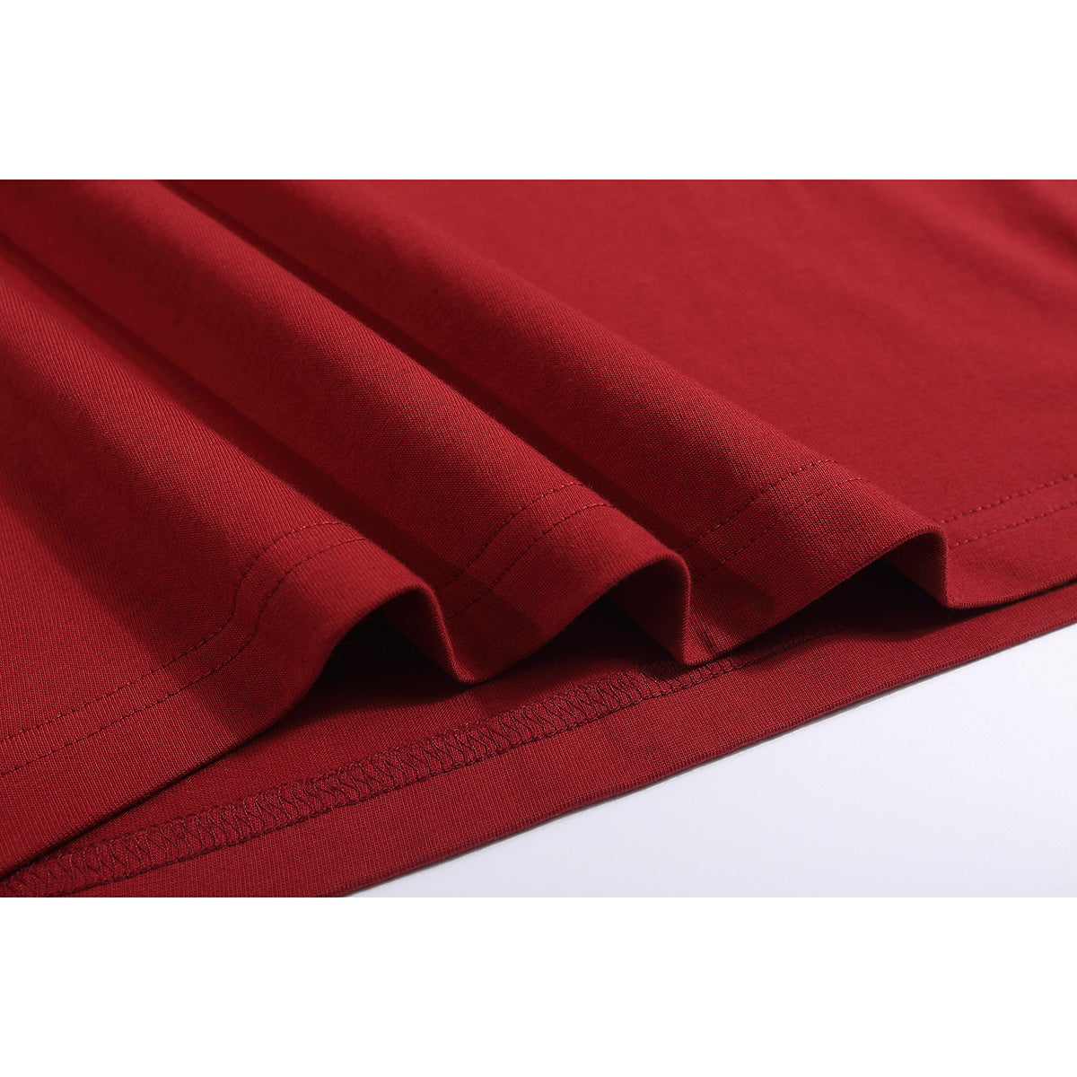 Close-up of the red T-shirt's folded hem and stitching.