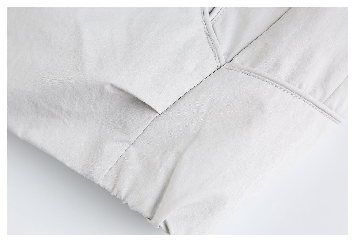 Close-up of pale gray garment seams and a folded panel with light contrast piping.