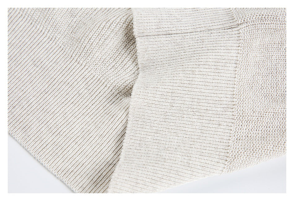 Close-up of an ivory knit sweater showing a broad ribbed section beside the textured knit.