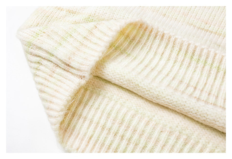 Close-up of the ivory sweater's ribbed knit hem and softly flecked fabric.
