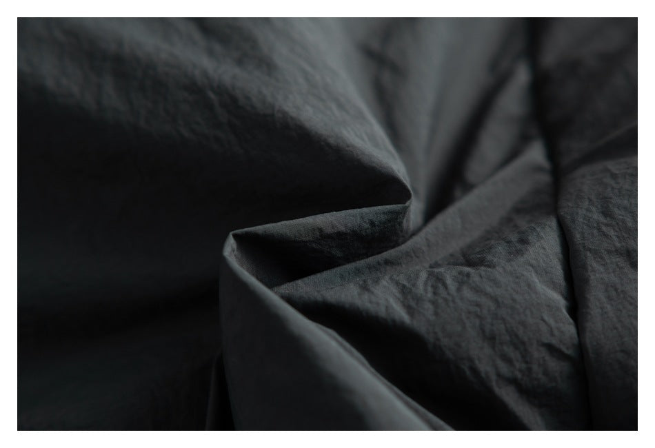 Extreme close-up of the dark, softly wrinkled garment surface.