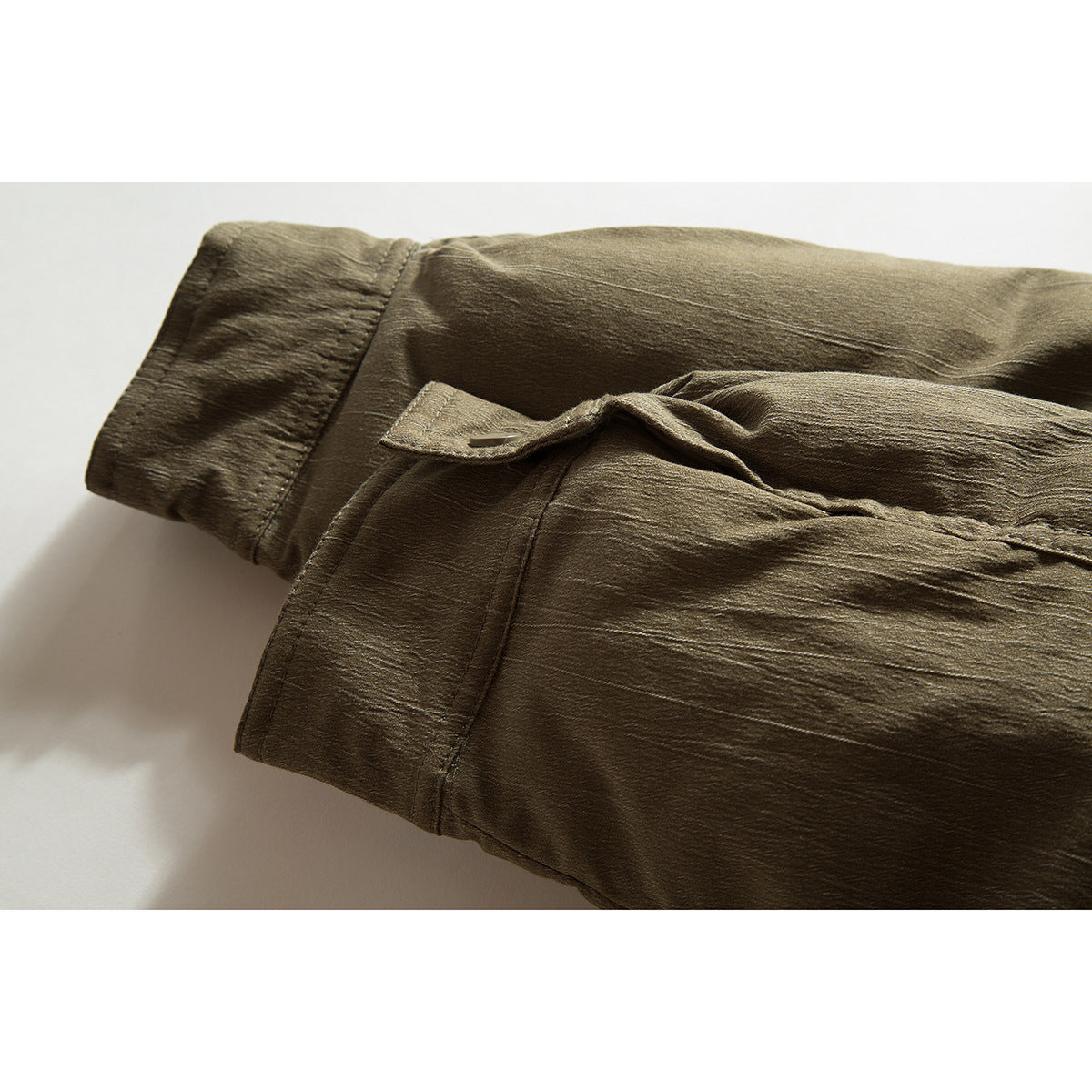 Close-up of an olive-brown jacket sleeve cuff and buttoned strap.