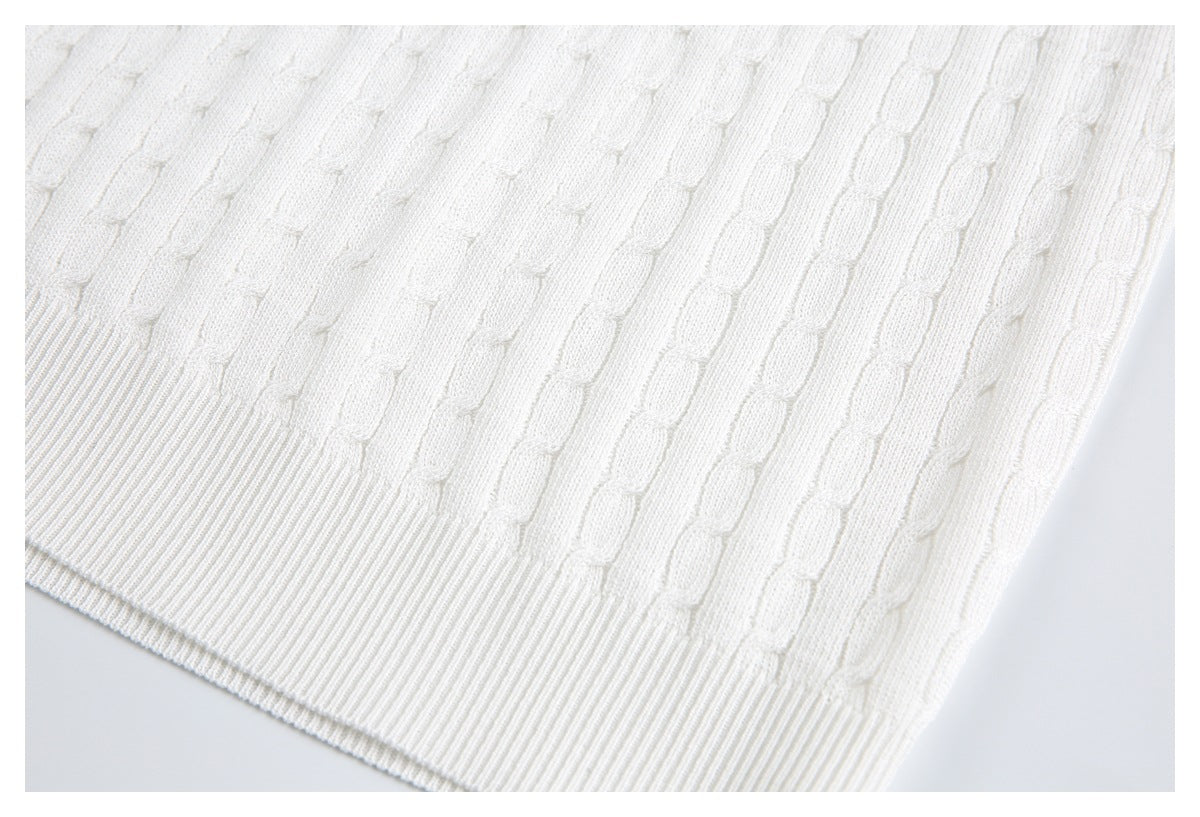 Close-up of the ivory knit garment's ribbed hem and raised vertical stitch pattern.