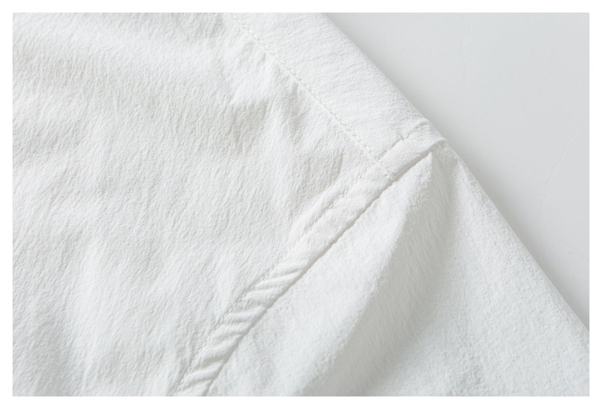 Close-up of white shirt fabric showing a curved stitched seam and folded edge.
