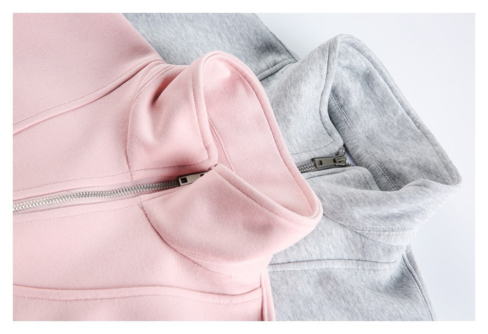 Close-up of pink and gray pullovers showing their high collars, neckline seams, and zipper details.