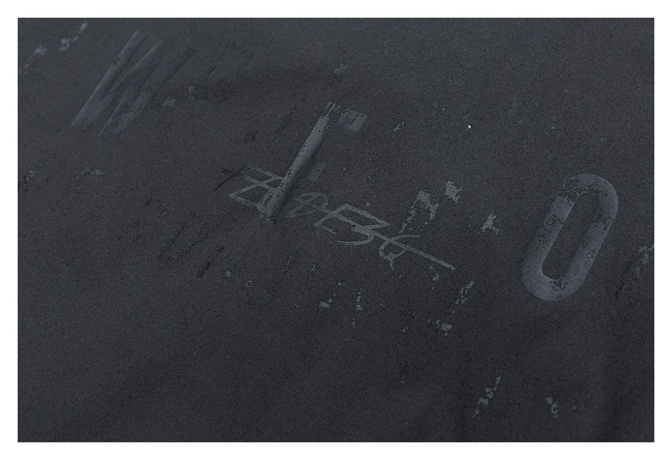 Close-up of dark fabric with a distressed, low-contrast printed graphic.