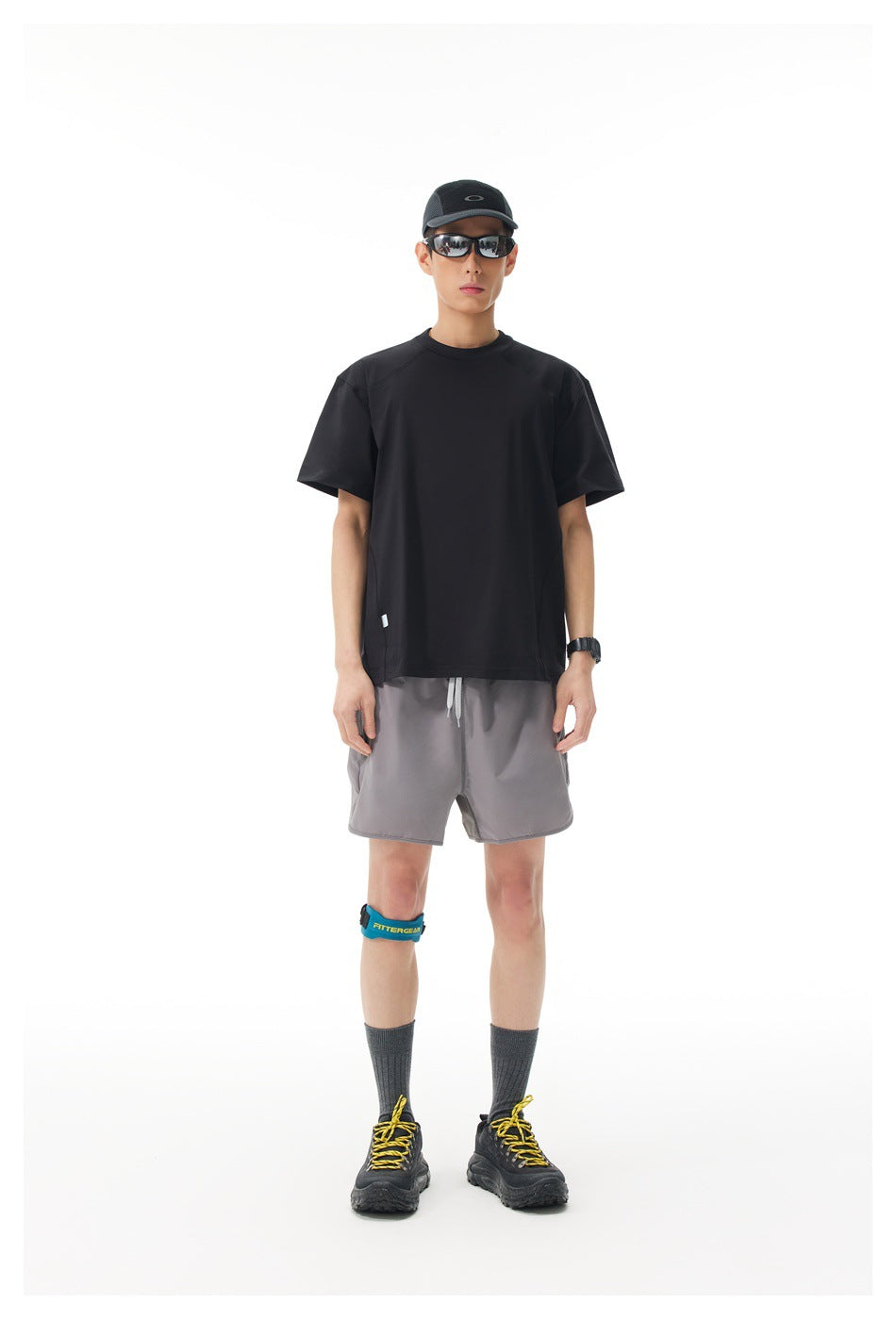 Front view of a model wearing a black short-sleeve shirt and gray athletic shorts.