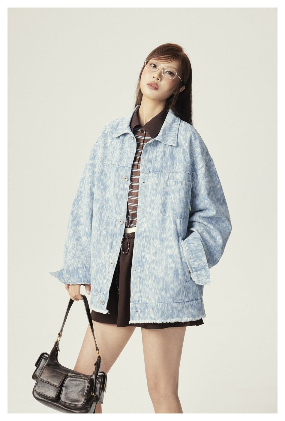 Model wearing an oversized pale blue mottled button-front jacket with chest pocket and frayed hem.