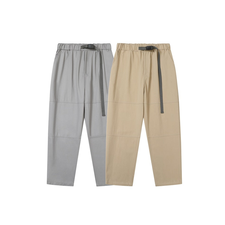 Front view of gray and tan pants with elastic waists, long black buckle straps, and straight legs.